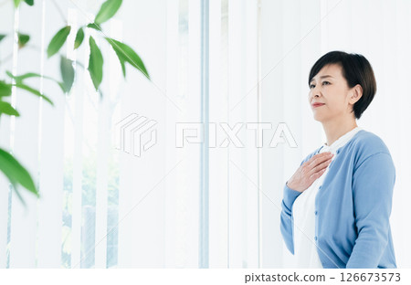 窗邊手放在胸前的中年婦女 126673573