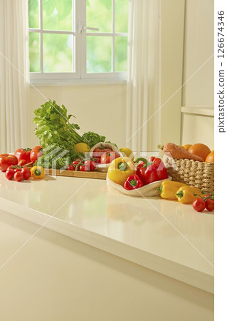 Several juice glasses sit on a kitchen island surrounded by fresh fruits and vegetables, presenting a colorful and healthy lifestyle setup. Blank space for presentation product 126674346