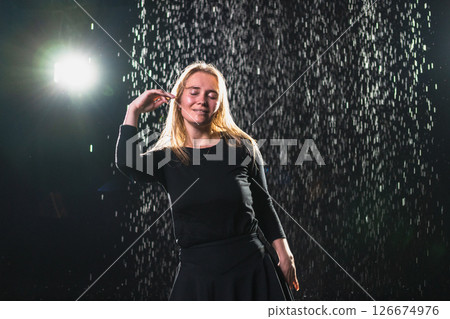 Contemporary woman dancer posing in rain water on black background. Female artist performer dancing with expression. Modern ballerina dancing in darkness. Passion dance in dark. Flexibility balance 126674976