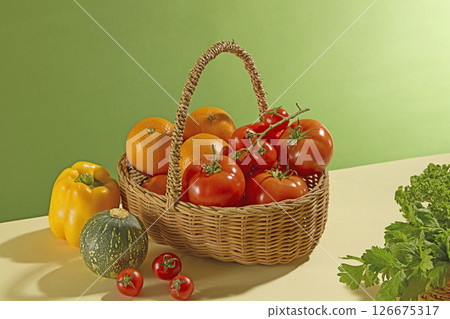 Flat shot of vegetables like squash, carrots and herbs placed in a wicker basket with handles on a green background. The vibrant colors highlight the freshness and organic style. 126675317