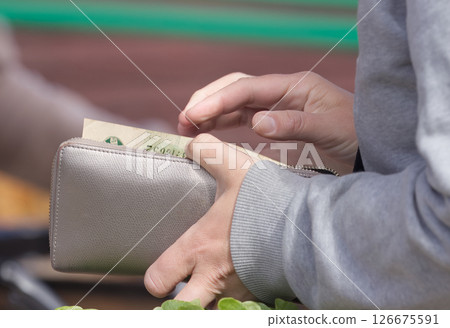 Hands Handling Money and Wallet in an Outdoor Market Setting Hands Handling Money and Wallet in an Outdoor Market Setting 126675591