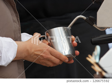 Close-Up of Hands Holding Milk Steaming Pitcher for Coffee Preparation Close-Up of Hands Holding Milk Steaming Pitcher for Coffee Preparation 126675592
