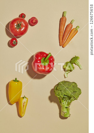 Top view of assorted vegetables such as tomatoes, carrots, bell peppers, and broccoli arranged creatively on a neutral beige background, perfect for food art visuals. Top view of assorted vegetables such as tomatoes, carrots, bell peppers, and broccoli arranged creatively on a neutral beige background, perfect for food art visuals. 126675658
