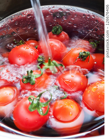 Bunch of fresh red cherry tomatoes rinsed in the bowl with water in the sink, close up of tomatoes in the bowl covered with water drops. 126676406