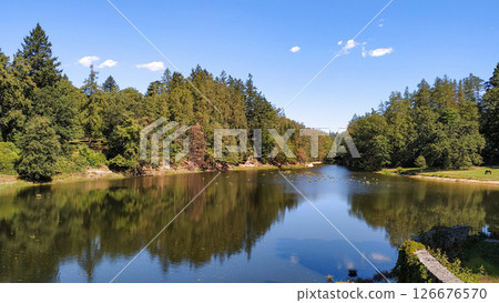 Lake reflecting trees and blue sky near cervena lhota castle in czechia 126676570