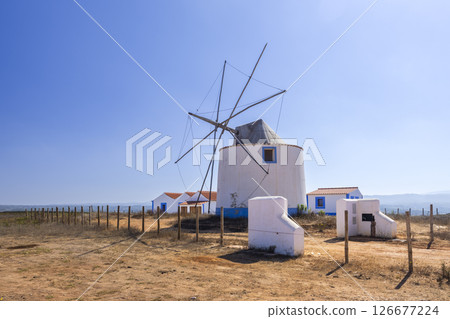 Traditional portuguese windmill standing in Algarve countryside under blue sky Traditional portuguese windmill standing in Algarve countryside under blue sky 126677224