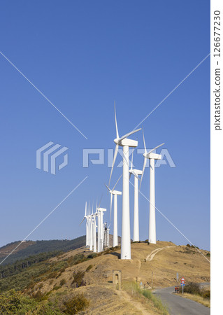 Wind turbines generating clean energy on a hilltop under a clear blue sky Wind turbines generating clean energy on a hilltop under a clear blue sky 126677230