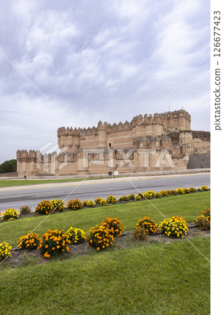 Coca Castle rising above flowerbeds in Coca, Segovia, Spain Coca Castle rising above flowerbeds in Coca, Segovia, Spain 126677423