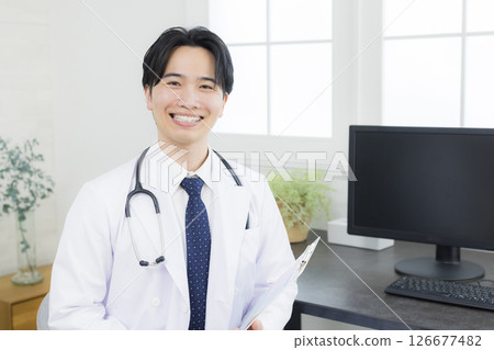 A man in a white coat talking in a consultation room A man in a white coat talking in a consultation room 126677482