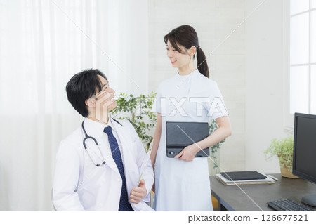 一名身穿白大褂的男子在檢查室與護士交談 一名身穿白大褂的男子在檢查室與護士交談 126677521