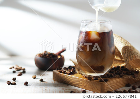 cold milk poured into iced coffee 126677841