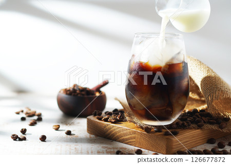 cold milk poured into iced coffee 126677872