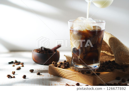 cold milk poured into iced coffee 126677892