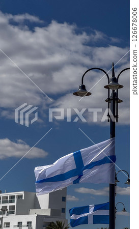 Flags of Greece and Cyprus attached to an ornate lamppost against blue skies in a coastal Cypriot town. 126678006
