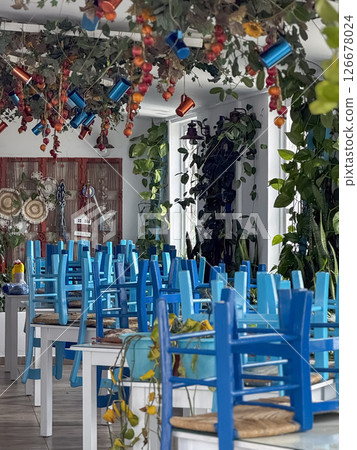 A traditional Cypriot outdoor taverna with blue chairs and tables beneath autumn foliage, evoking local charm. 126678024