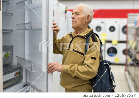 Senor man pensioner buying fridge in showroom of electrical appliance store Senor man pensioner buying fridge in showroom of electrical appliance store 126678557