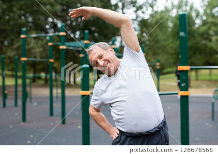 Elderly man doing gymnastics on an outdoor sports ground Elderly man doing gymnastics on an outdoor sports ground 126678568