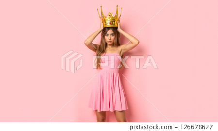 Young woman in pink dress placing large gold crown on head, unimpressed face, sarcastic mood, funny pose, royalty concept, satire theme, modern queen, humorous fashion, playful attitude Young woman in pink dress placing large gold crown on head, unimpressed face, sarcastic mood, funny pose, royalty concept, satire theme, modern queen, humorous fashion, playful attitude 126678627