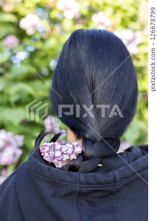 Dark haired girl with lilac flowers on her hair. Rear view. 126678799