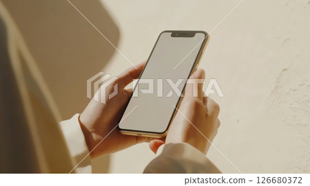 Close up of a businesswoman holding a smartphone with a blank screen, suggesting the potential for mobile app development, marketing, or social media engagement 126680372