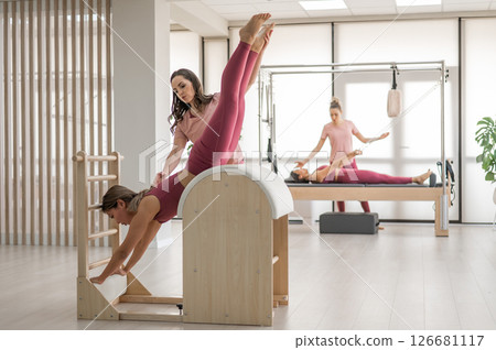 A trainer adjusts woman on a Ladder Barrel. 126681117
