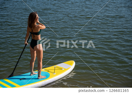 Caucasian woman riding a SUP board on the lake. Summer sport. 126681165