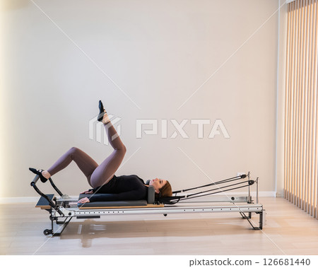 Woman doing pilates on reformer. Woman doing pilates on reformer. 126681440