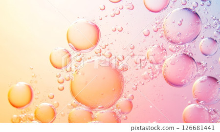 Captivating abstract close up featuring various bubble sizes with translucent surfaces reflecting a soft gradient light from warm peach to cool rosy pink 126681441