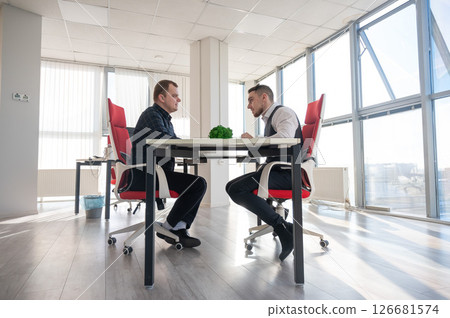 Two Caucasian men communicating at a business meeting.  126681574