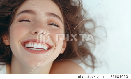 Young woman with closed eyes is lying on white background showing her beautiful smile and perfect white teeth after cosmetology or dentistry treatment 126681610