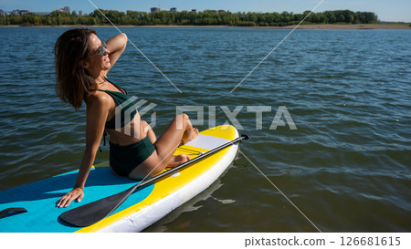 Beautiful caucasian woman is swimming on a SUP board. 126681615