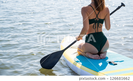 Caucasian woman riding a SUP board on the lake. Summer sport. Caucasian woman riding a SUP board on the lake. Summer sport. 126681662