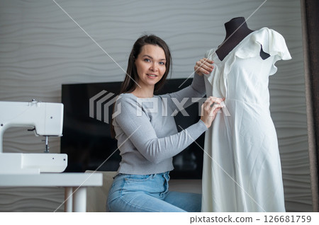 Caucasian woman sews a dress at home. Workspace of a seamstress 126681759