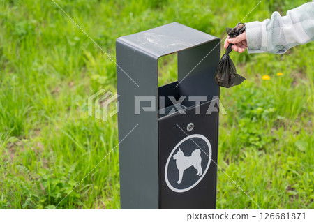 Responsible Dog Owner Disposing of Waste in Park Bin.  126681871