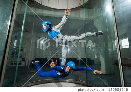 A male instructor teaches a woman how to fly in a wind tunnel. Free fall simulator. 126681946