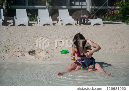 Caucasian woman applies sunscreen to her one-year-old son's skin. Caucasian woman applies sunscreen to her one-year-old son's skin. 126681960