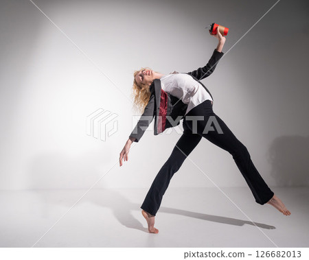 Barefoot ballerina in business suit dancing with a cup of coffee on a white background.  126682013