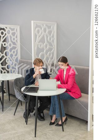 Colleagues are sitting at a laptop and discussing work.  126682170