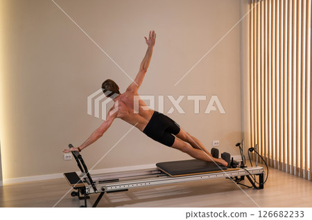 A man doing Pilates on a reformer. A man doing Pilates on a reformer. 126682233
