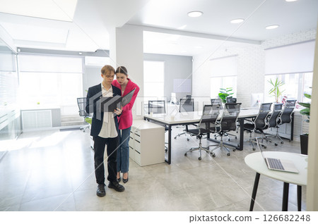 Colleagues look at a folder with documents and discuss work issues.  126682248