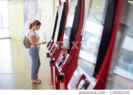 Caucasian woman pays at selfservice machine with contactless phone payment. Caucasian woman pays at selfservice machine with contactless phone payment. 126682293