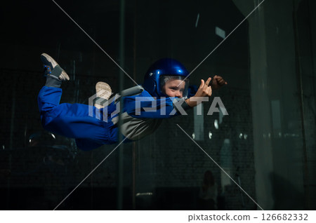 Caucasian boy flies in a wind tunnel.  126682332