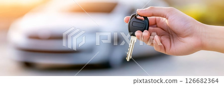 Salesperson holding car keys in front of a sleek new vehicle, symbolizing a successful purchase or rental agreement within a bustling dealership showroom Salesperson holding car keys in front of a sleek new vehicle, symbolizing a successful purchase or rental agreement within a bustling dealership showroom 126682364