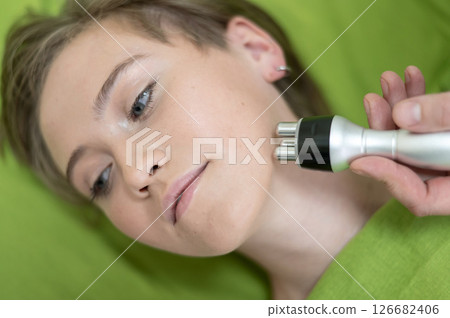 Top view of Caucasian woman undergoing radio wave RF lifting procedure in beauty salon.  126682406