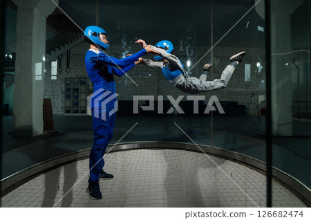 A male instructor teaches a woman how to fly in a wind tunnel. Free fall simulator. 126682474