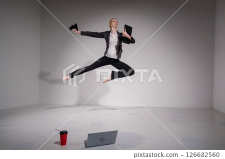 Barefoot ballerina in business suit jumping with laptop on white background. Barefoot ballerina in business suit jumping with laptop on white background. 126682560