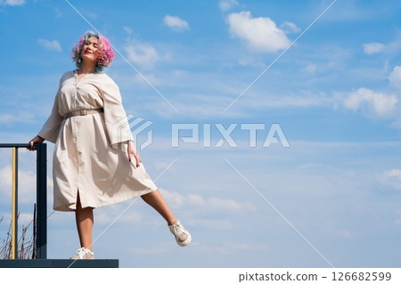 A woman with colored hair walks outdoors. Portrait of a girl against the blue sky. A woman with colored hair walks outdoors. Portrait of a girl against the blue sky. 126682599