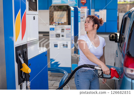Woman refueling car with gasoline at self-service gas station. Woman refueling car with gasoline at self-service gas station. 126682831