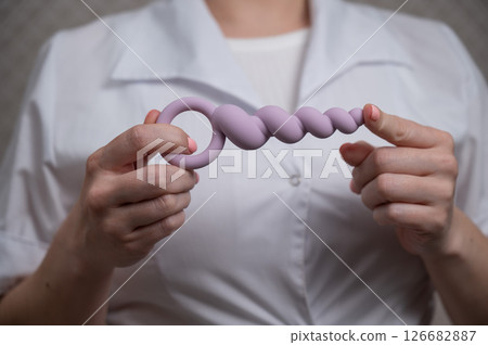 Woman in doctor's coat holding anal beads. Woman in doctor's coat holding anal beads. 126682887