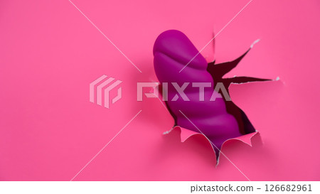 Raspberry sex toy sticks out of pink paper background. Copy space.  126682961